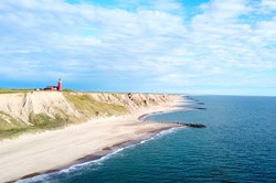 Panoramic aerial view of Bovbjerg Fyr lighthouse, cliffs and North Sea in summer with blue sky