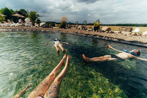 Drei junge Menschen treiben im Wasser des Außenbeckens der Kristall Therme Bad Wilsnack