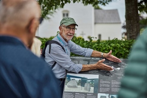 Ein Guide zeigt das Welterbe-Poster im Museum Kongernes Jelling