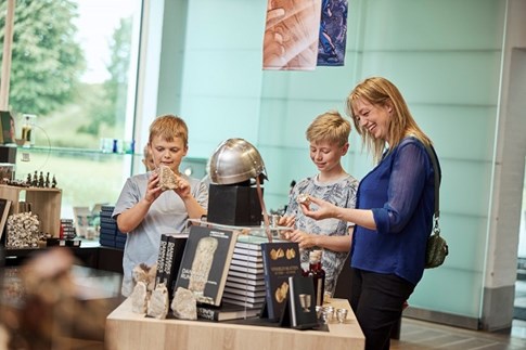 Eine Familie betrachtet die Produkte im Museumsshop von Kongernes Jelling
