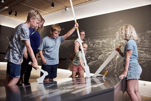 Kinder probieren Wikingerwaffen im Erlebniscenter des Museums Kongernes Jelling aus