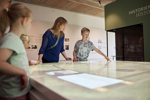 Eine Familie betrachtet die digitalen Displays im Museum Kongernes Jelling