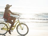 Frau auf Fahrrad vor dem Meer mit Sonnenuntergang