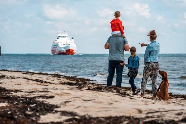  Eine Familie mit Kindern und Hund betrachtet die FRS Syltfähre vom Strand aus