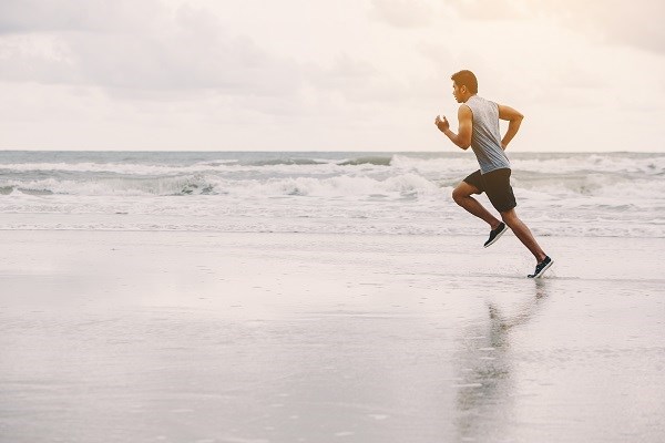 Jogger am Strand vor Wellen und Meer 