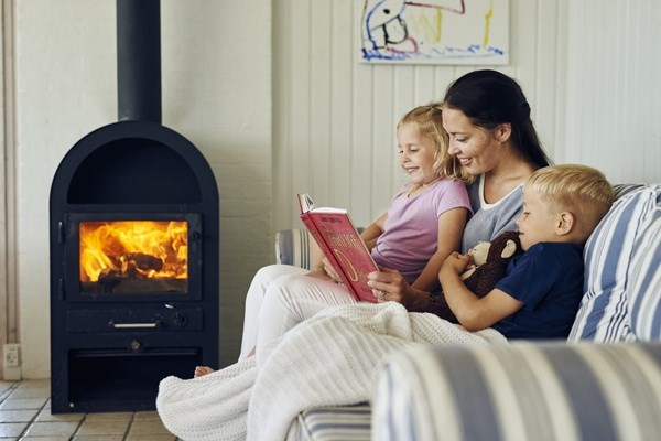 Eine Mutter liest ihren zwei Kindern am Kamin ein Buch vor
