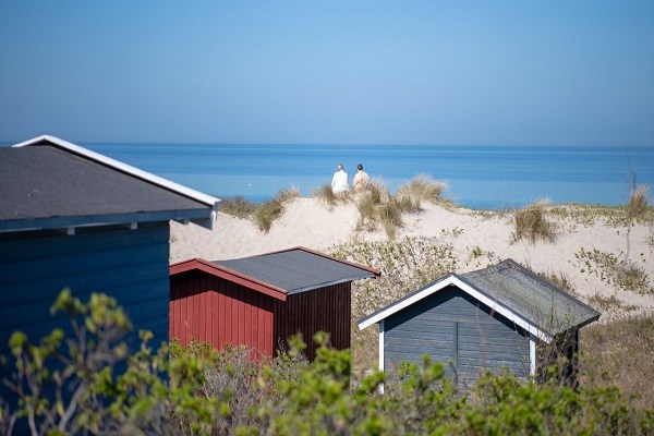 Zwei Frauen am Strand von Tisvildeleje mit Strandhäusern im Hintergrund