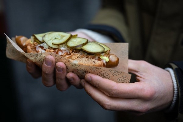 Zwei Hände, die einen dänischen Hotdog halten