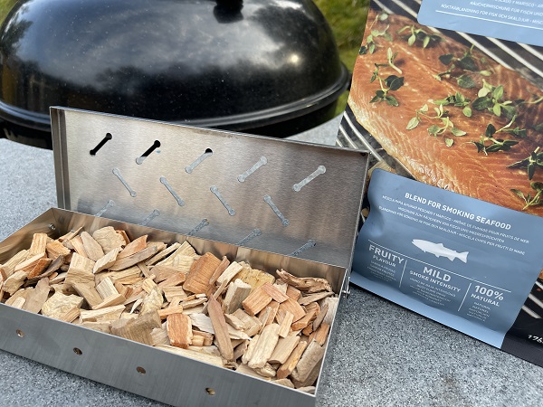 Raeucherchips aus Holz in Raeucherbox vor Kugelgrill