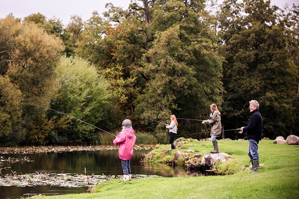 Eine Familie, bestehend aus Mama, Papa und zwei Töchtern, angelt am See