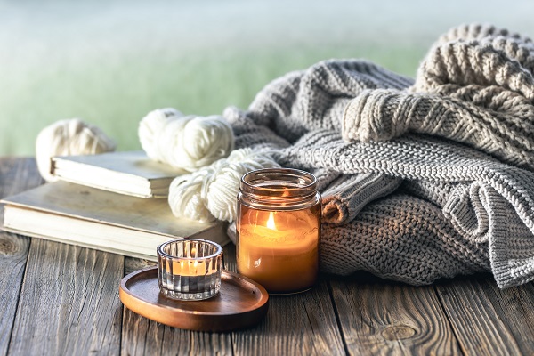 Bücher, Kerzen und Strickwaren liegen auf einem Holztisch