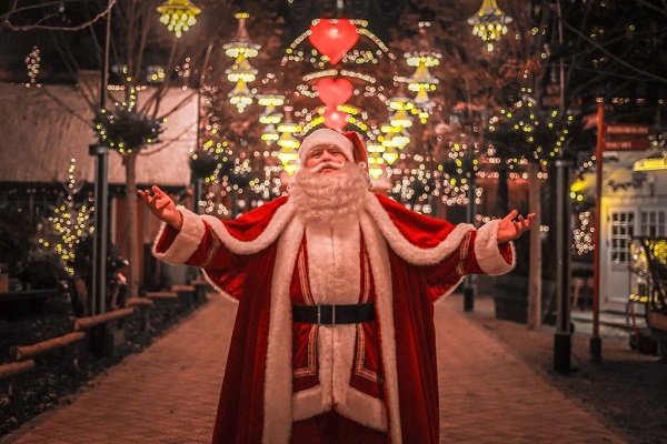 Der Weihnachtsmann breitet seine Arme im festlich geschmückten Tivoli aus