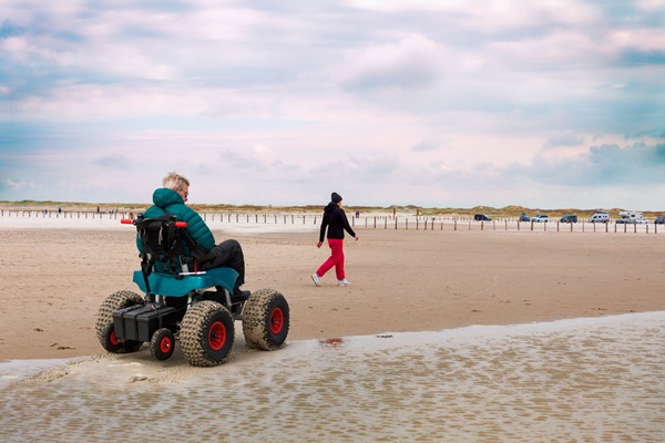 Ein Mann im Strand-Rollstuhl mit Elektroantrieb