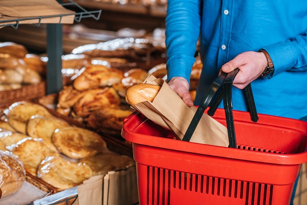 Ein Mann mit einem roten Einkaufskorb kauft im Supermarkt frisches Brot