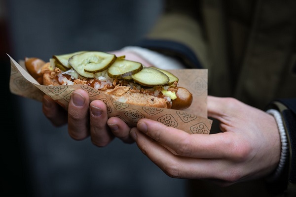 Zwei Hände, die einen dänischen Hotdog halten