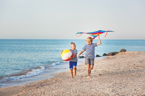 Kinder spielen am Strand mt Ball und Drachen
