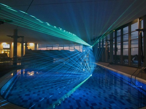Schwimmbecken bei Nacht mit Indoor Lasershow 