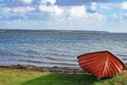 Ein orangenes Fischerboot liegt am Ufer der Nissum Brending bei Agger Havn in Dänemark