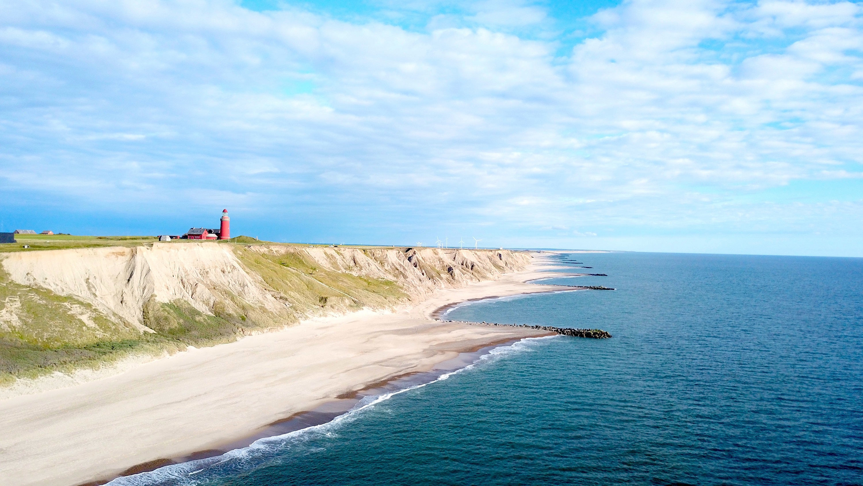 Panoramic aerial view of Bovbjerg Fyr lighthouse, cliffs and North Sea in summer with blue sky