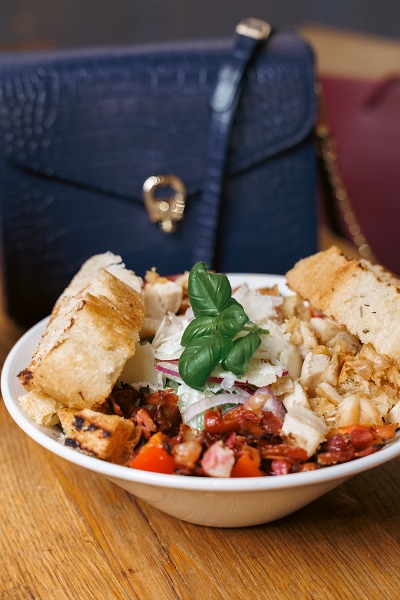 Eine Schüssel Salat mit einer Handtasche im Hintergrund