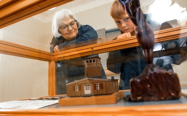 Eine Oma und ihr Enkel betrachten ein Modell des Fröslevlagers