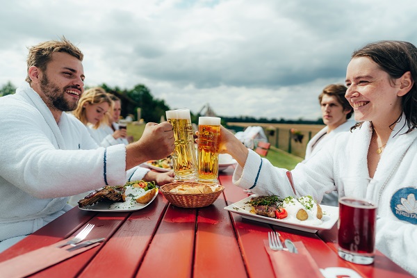 Ein lächelndes Paar, das in der Kristall Therme Bad Wilsnack anstößt und Steak isst