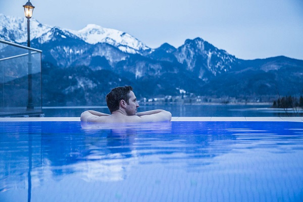 Ein Mann geniesst den Ausblick vom Aussenbecken der Kristall Therme Kochel am See
