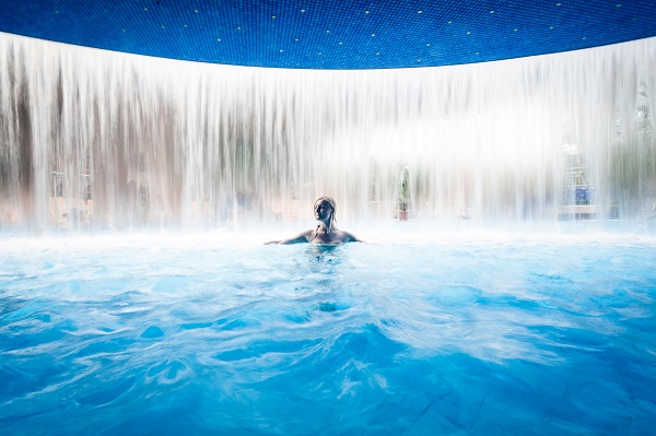 Eine Frau unter dem Wasserfall in der Kristall Wohlfühltherme Ludwigsfelde