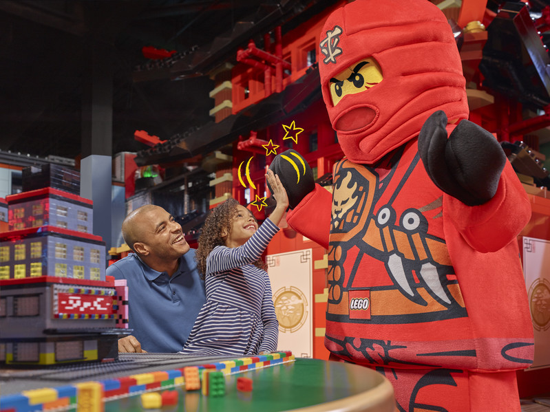Ein Mädchen gibt einem lebendigen LEGO Ninjago-Figur ein High Five im LEGOLAND Discovery Centre Oberhausen