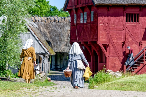 Zwei Frauen aus dem Mittelalter tragen Wäsche durch das Dorf